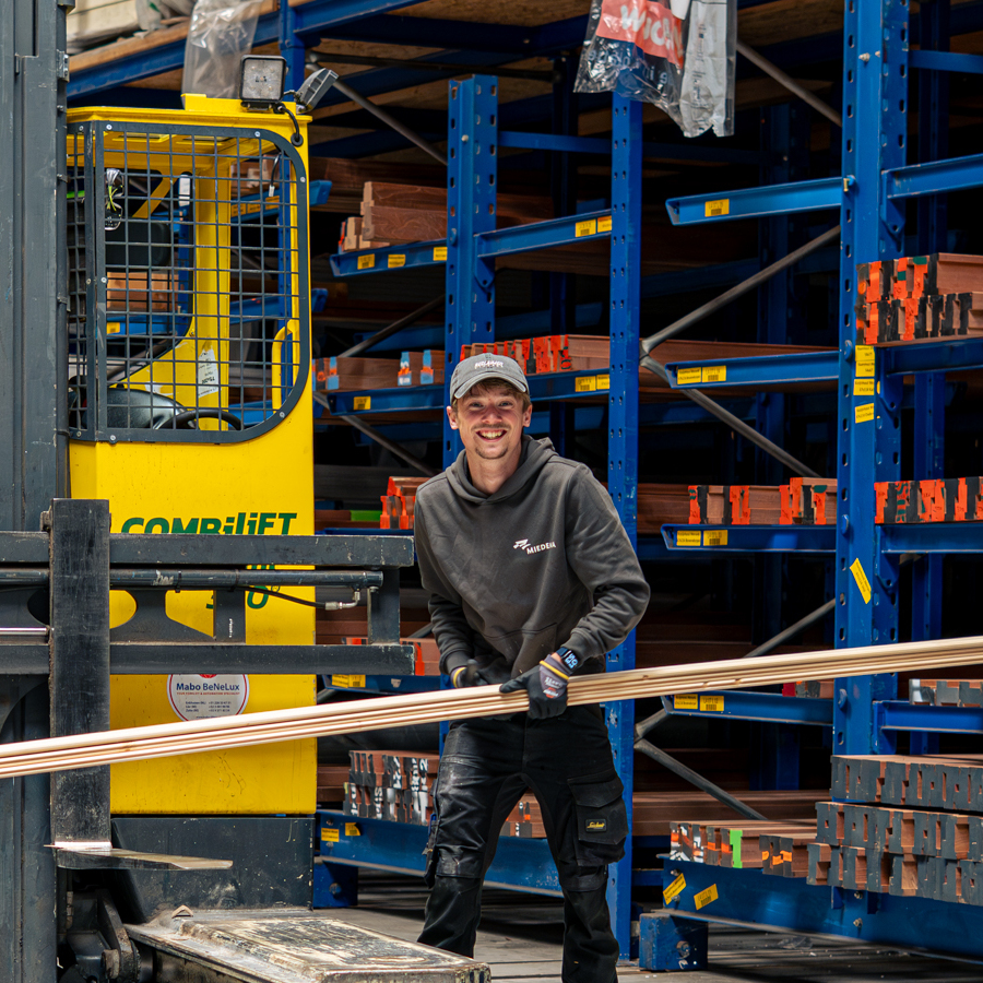 Lachende Miedema-medewerker verplaatst koperen buizen door het magazijn langs de heftruck